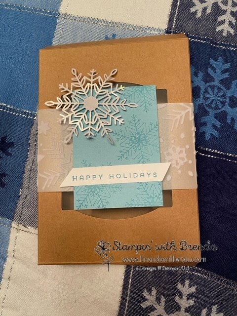 Kraft gift box with window wrapped with snowflake vellum and snowflake tag in blue and white with Happy Holidays