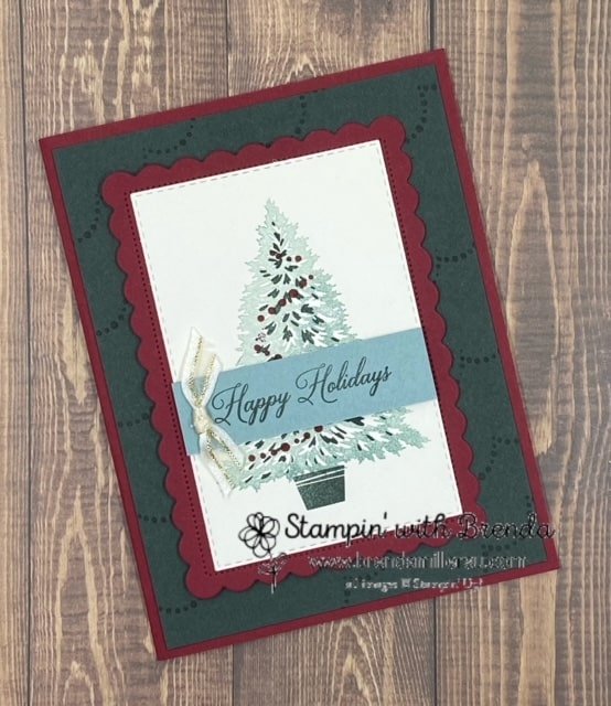 Christmas card with Cherry Cobbler and Evening Evergreen base with decorated tree in center overlaid with Happy Holidays and a bow