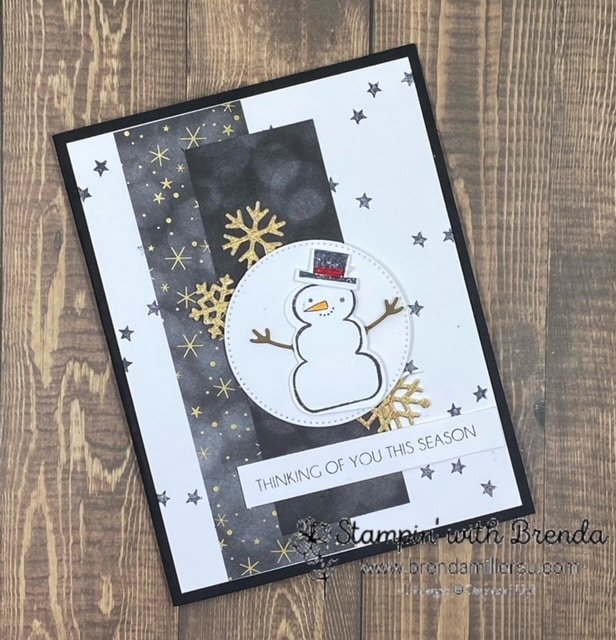 Black card base with white panel and black stars with black and gold accents and a snowman saying Thinking of you this season