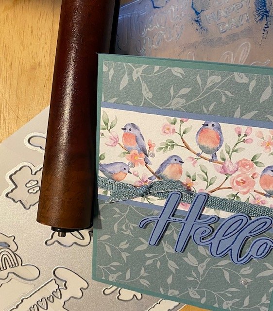 Brayer Thoughtful Moments Embossing Folder from Stampin' Up! to create Hello in blue with green background and little birds from Flight and Airy DSP